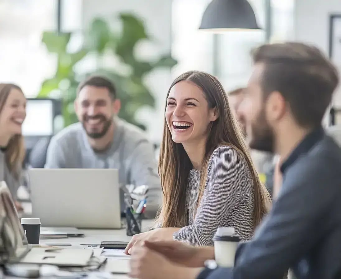 Group of People SItting at a desk witha computer open and smiling-1